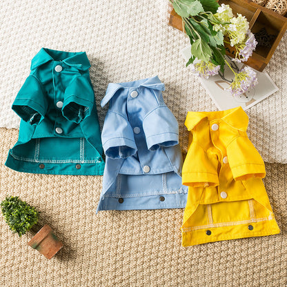 Gros plan sur les trois variantes du manteau en denim pour chien Billie : turquoise, bleu pâle et jaune vif, disposés sur un tapis en laine avec une décoration de fleurs printanières.