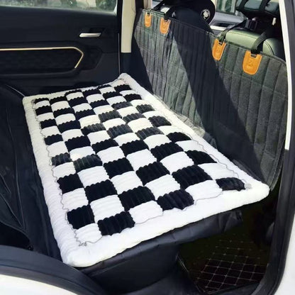 Banquette arrière de voiture protégée par une housse noire avec un tapis moelleux à damier noir et blanc, offrant un design moderne et confortable.
