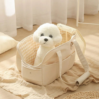 Petit chien blanc de type Bichon assis à l'intérieur d'un sac de transport en coton beige ouvert, révélant une doublure à motif vichy jaune et blanc.