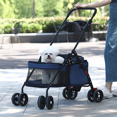 Petit chien Shih Tzu assis dans la poussette MobilConfort grise en extérieur, montrant le design compact, les roues maniables et la fenêtre de ventilation en mesh.