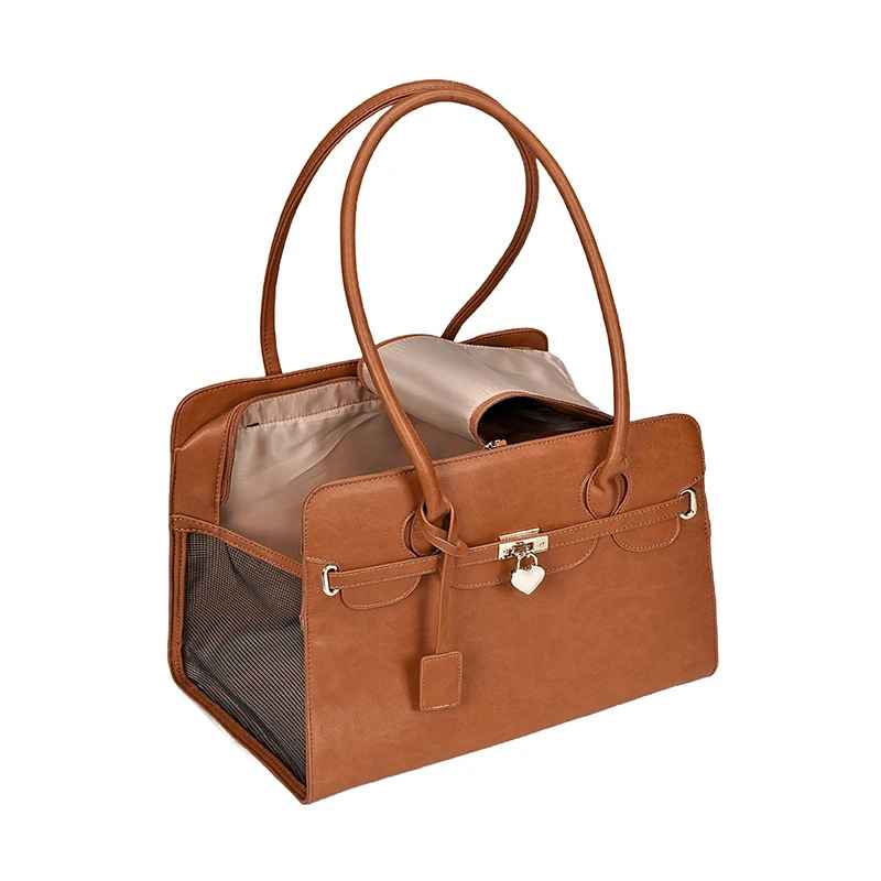 Sac de transport pour chien en cuir PU brun-fauve, modèle Le Porte Bonheur, avec détails de coutures apparentes, charms en forme de cœur et filet d'aération latéral.