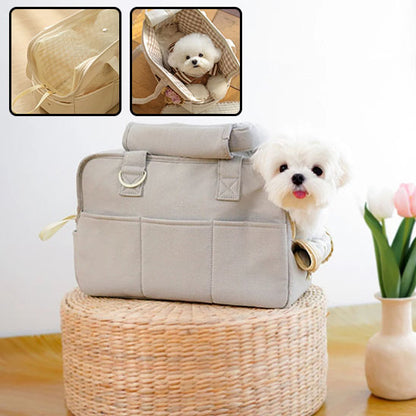 Petit chien blanc de type Bichon dont la tête dépasse d'un sac de transport en coton gris posé sur un panier en osier renversé.