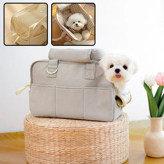 Petit chien blanc de type Bichon dont la tête dépasse d'un sac de transport en coton gris posé sur un panier en osier renversé.