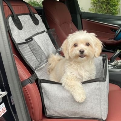 Petit chien blanc installé dans le siège auto Sécuri-Voyage en tissu gris chiné, fixé sur un siège de voiture en cuir marron pour un transport sécurisé.
